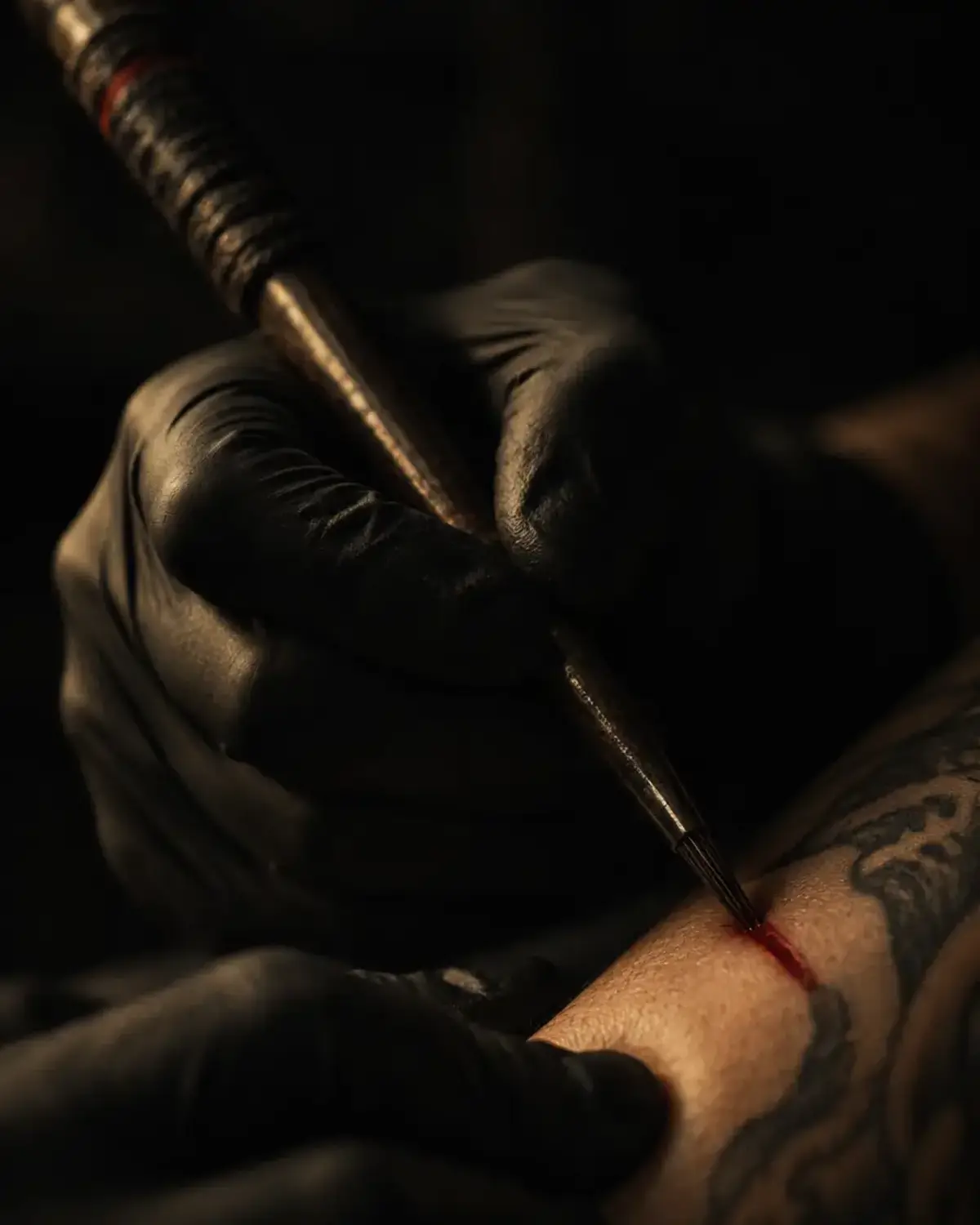 A gloved hand holding a tebori rod